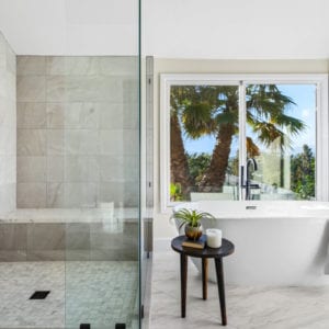Master bathroom with soaking tub and large grey tiled shower with black matte fixtures in Camarillo by JRP Design and Remodel