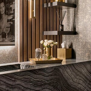 Modern bathroom with a sleek black marble sink, gold faucet, wooden accents, and a decorative tray with flowers and toiletries exuding sophisticated glamour. A framed black and white photograph hangs on the wall.