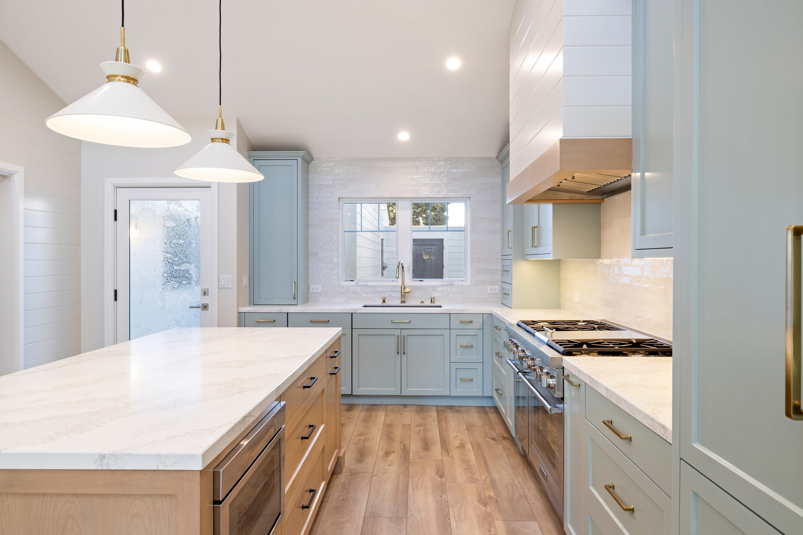 Bright blue kitchen with white countertops, stainless steel appliances, and wooden floors.