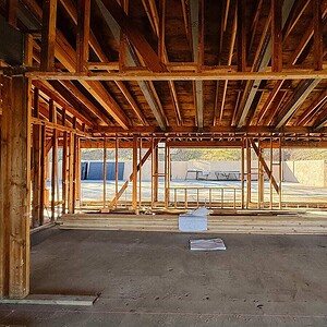 Interior view of new house framing under construction, showcasing wooden beams and structure.