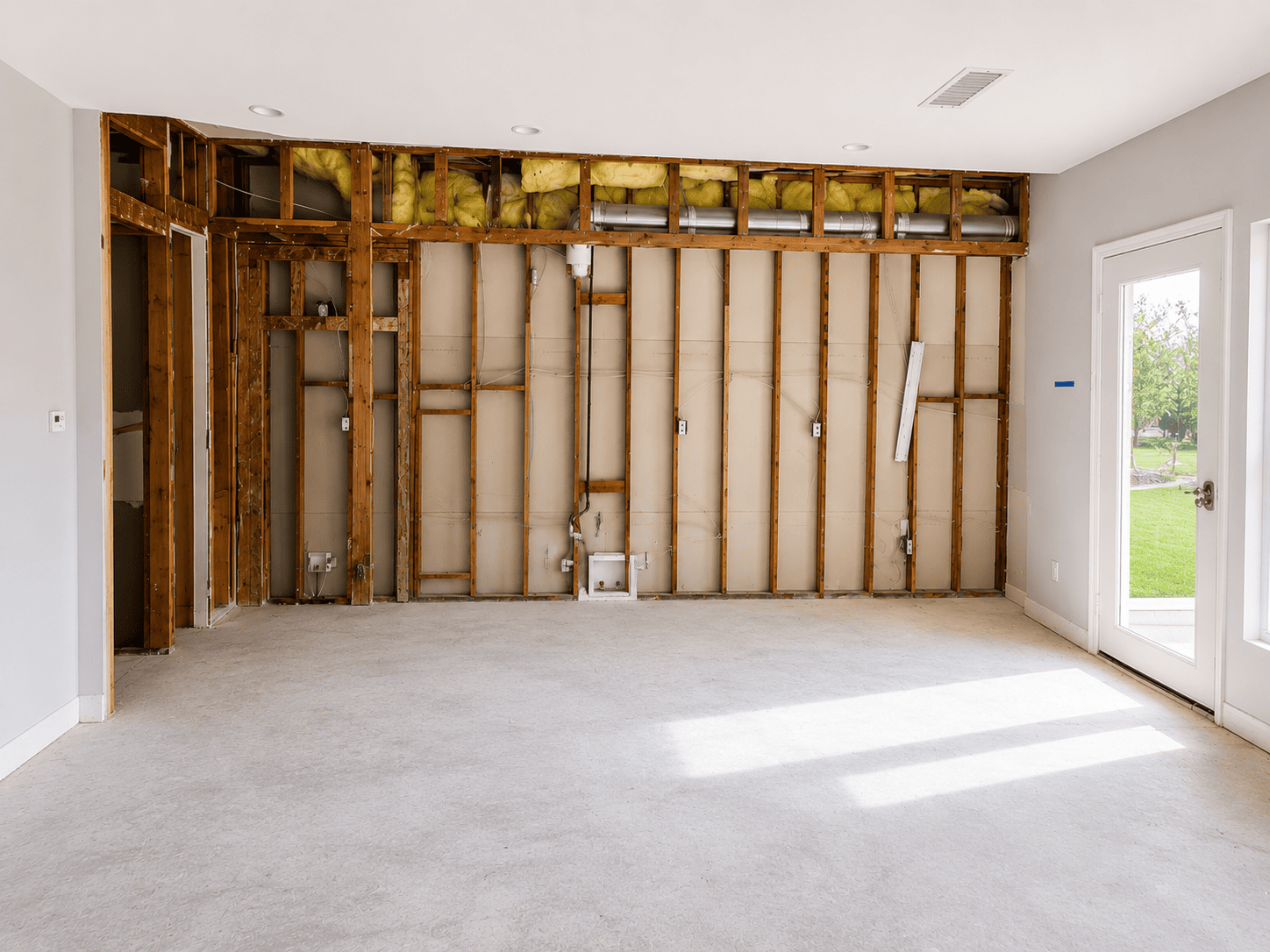 Unfinished kitchen with exposed wall framing and insulation.