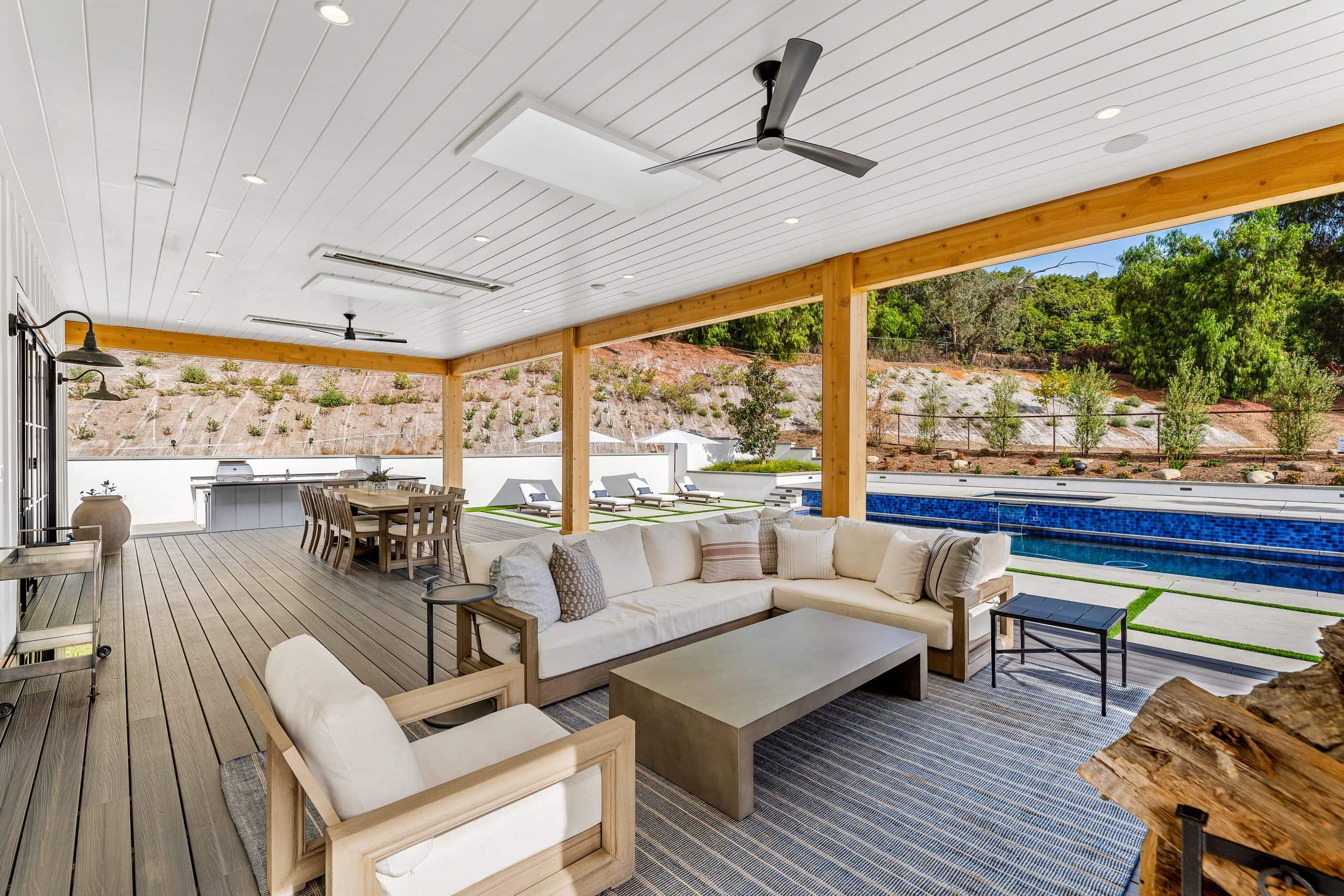Spacious outdoor covered patio with seating, pool, and scenic landscape view.