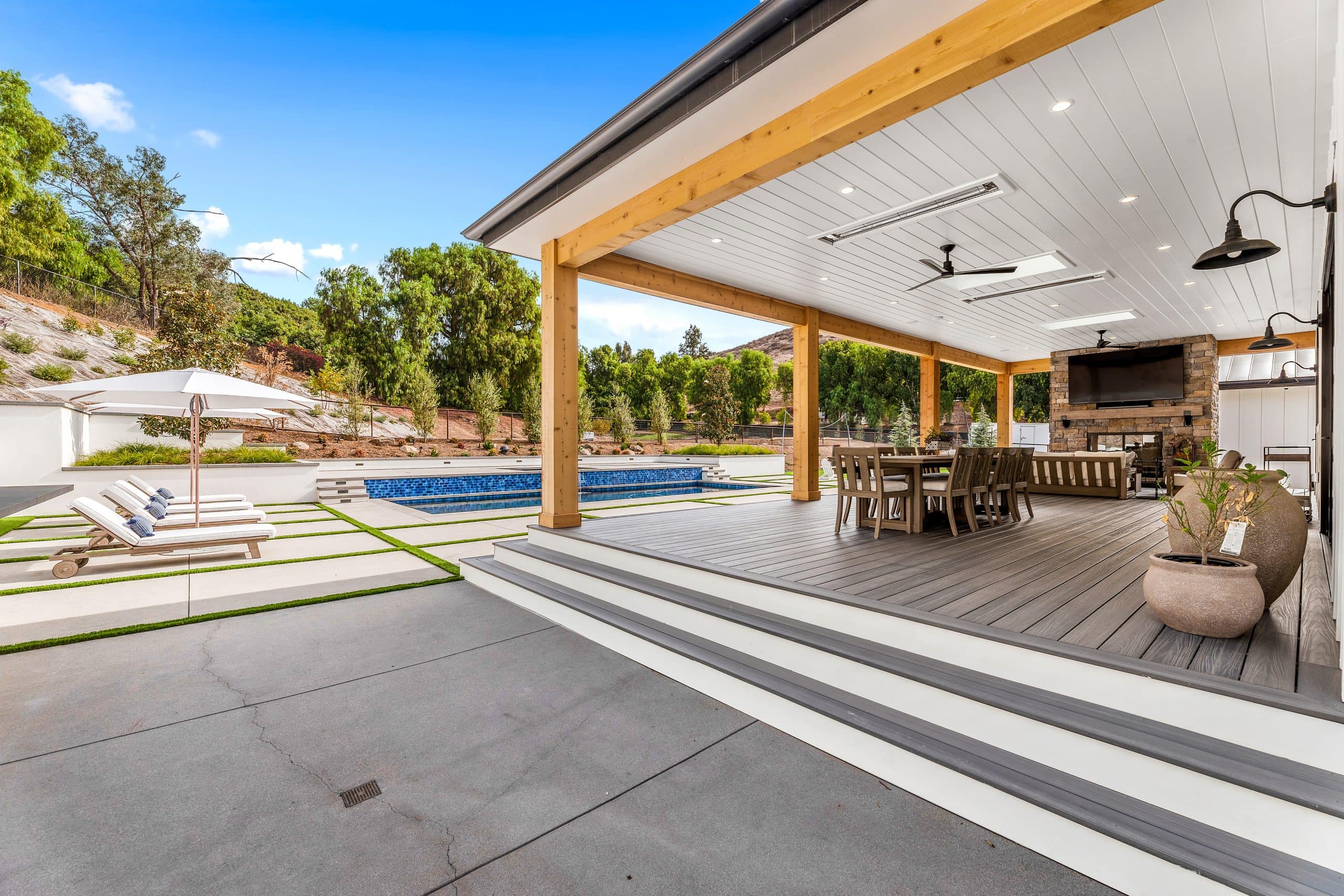 Spacious outdoor covered patio with pool, seating, and fireplace in modern farmhouse style.