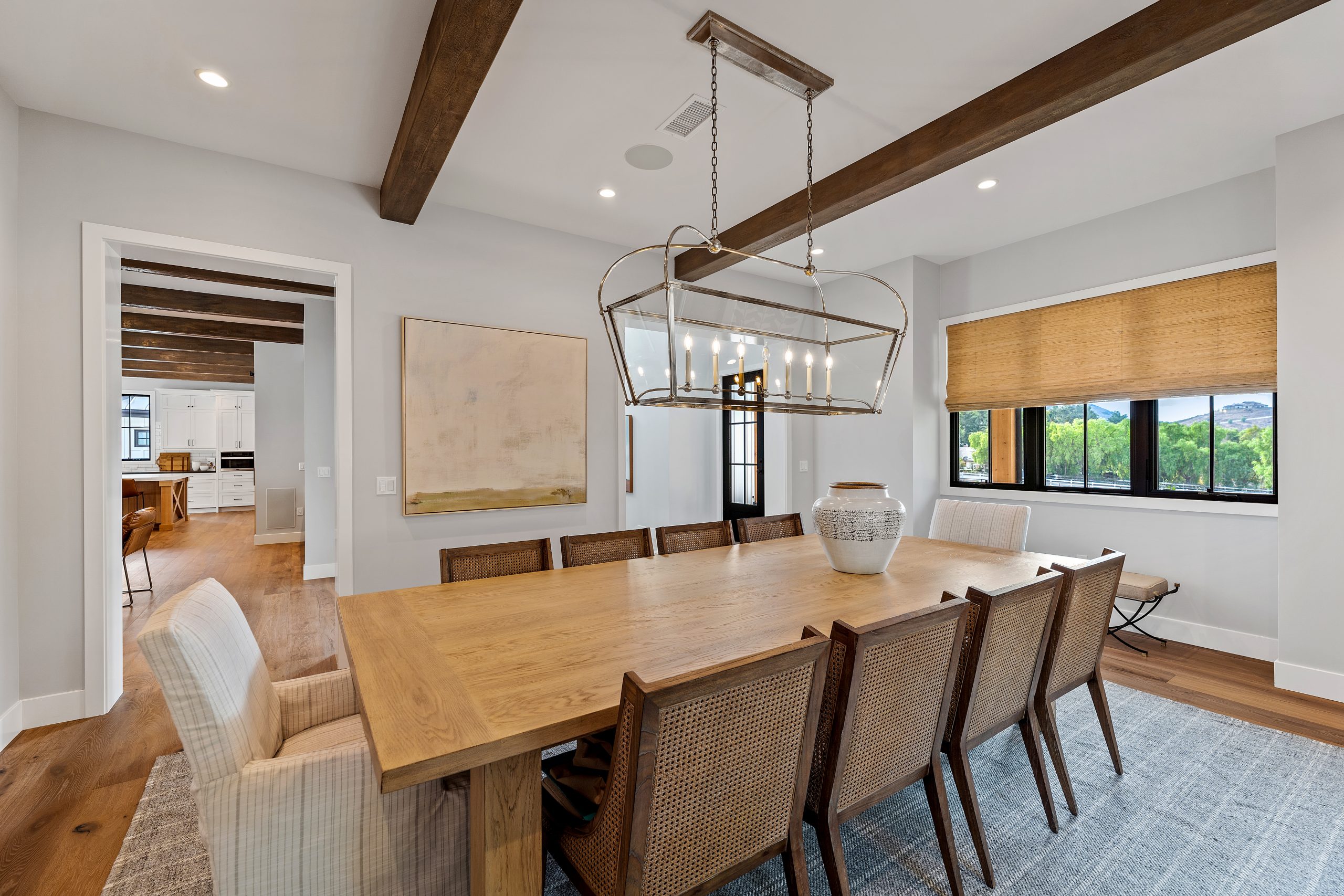 Elegant dining room with wooden beams, large table, and modern decor.