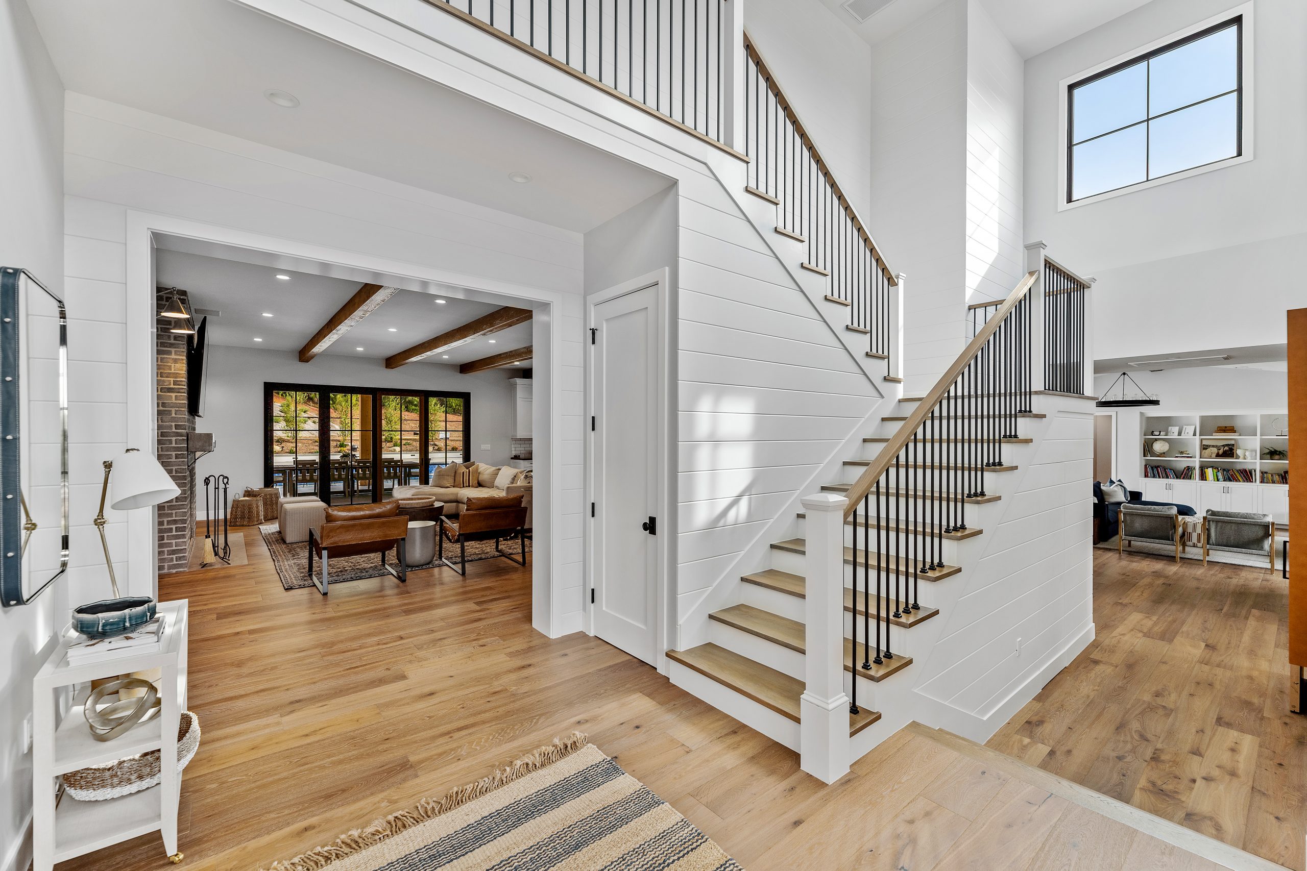 Bright, spacious modern farmhouse interior with staircase and open living area.