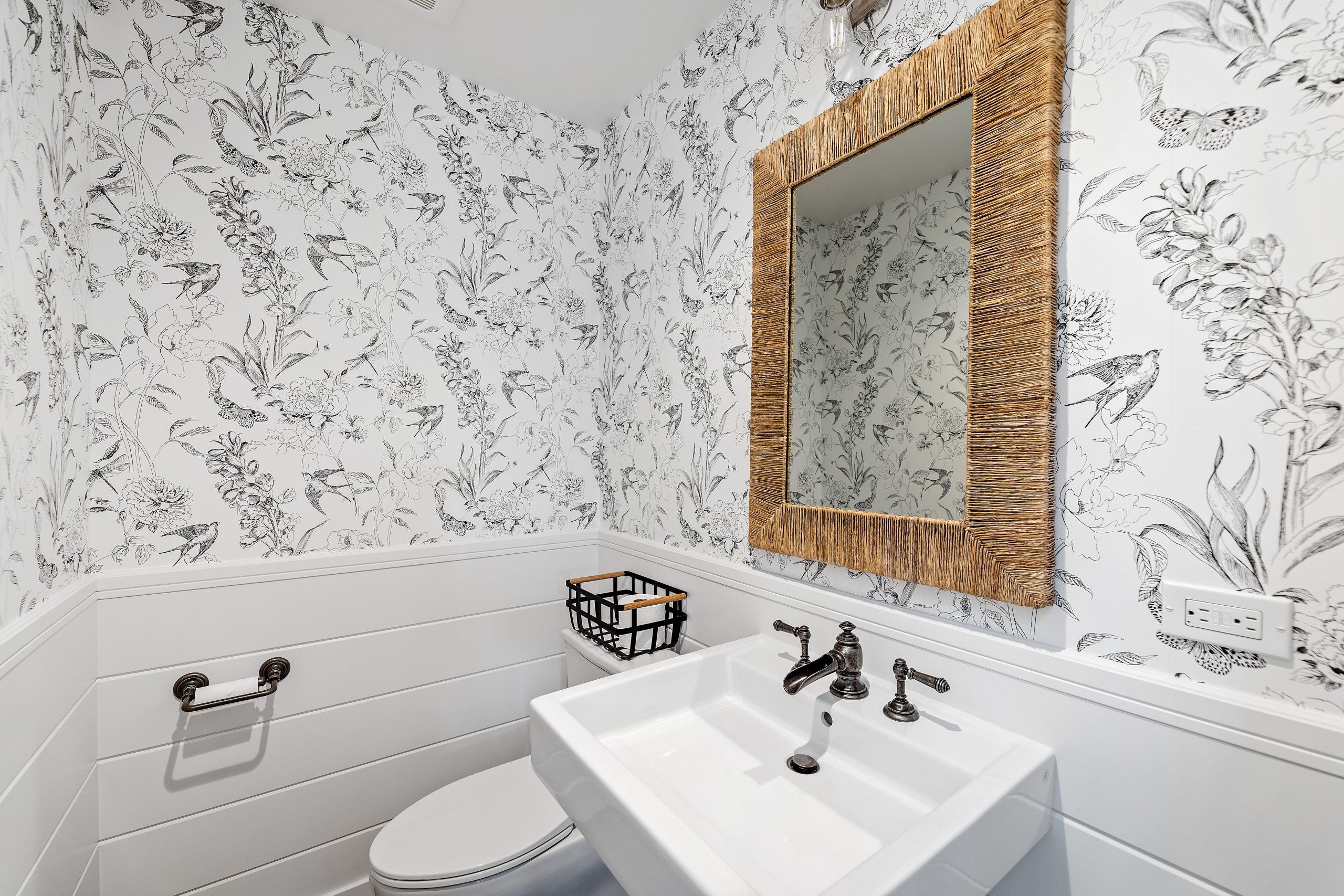 Charming farmhouse bathroom with floral wallpaper, white sink, and wooden mirror.