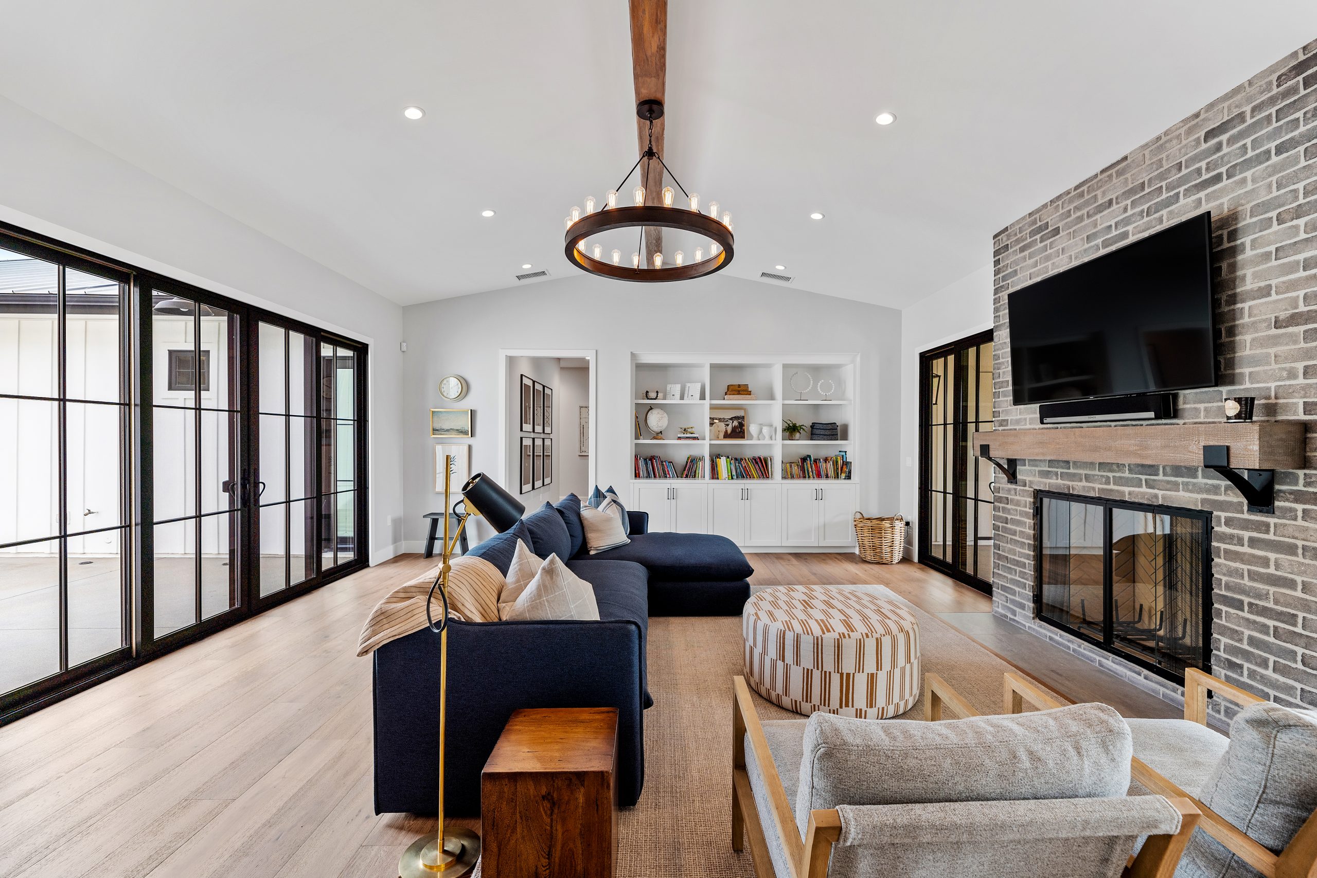 Spacious modern farmhouse living room with brick fireplace and large windows.