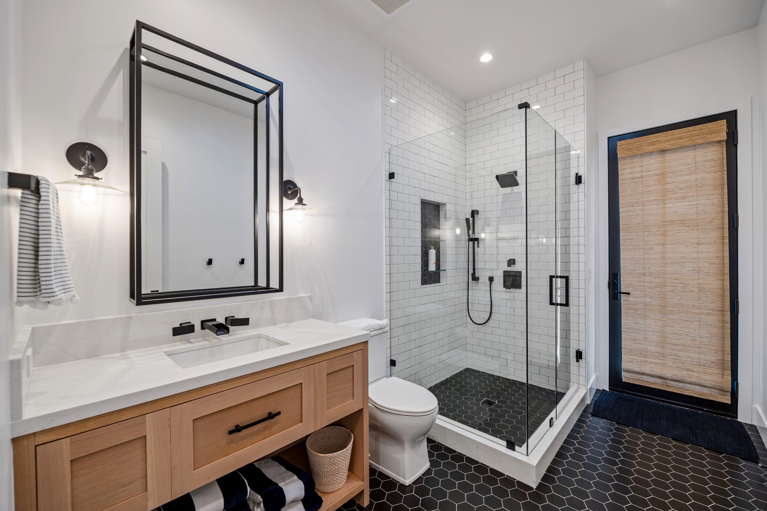 Contemporary bathroom with walk-in shower, wooden vanity, and black fixtures.